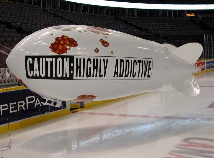 Giant Helium Blimp with text caution: highly addictive